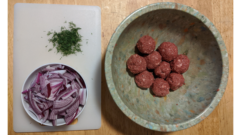 Uncooked meatballs, red onion, and dill