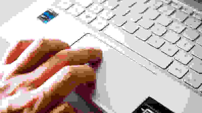 A close up of a person's fingers touching a trackpad on a laptop.