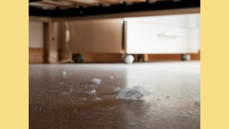 Detail of dust and dirt heap accumulated on a parquet floor under a bed.