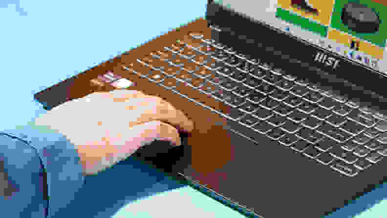 A hand rests on the track pad of the MSI Modern 15 (2023) laptop.