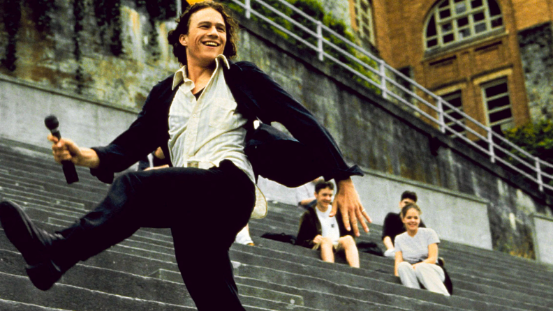 Actor Heath Ledger sings a love song from the bleachers in the 1999 teen romcom 10 Things I Hate About You.