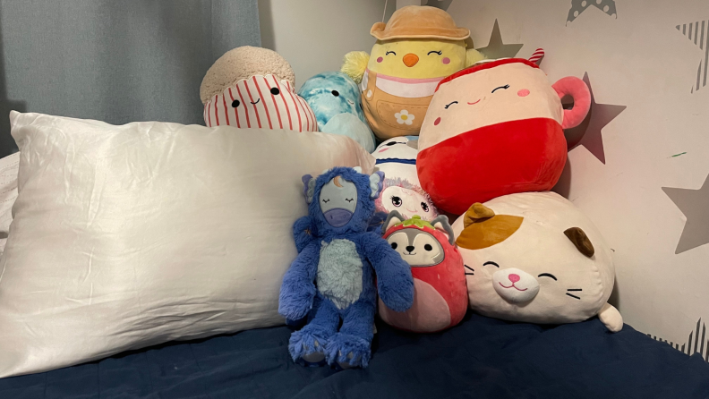 Plush stuffed animals on bed next to pillow.