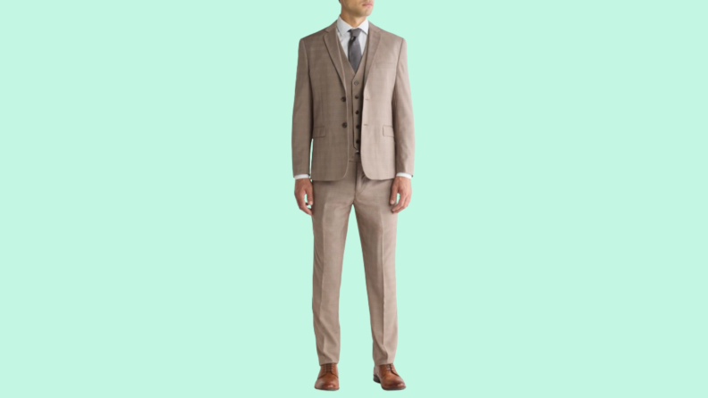 Man in dark tan suit and pants against teal background