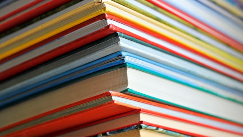 Close up shot of vertically stacked pile of multi-colored books.