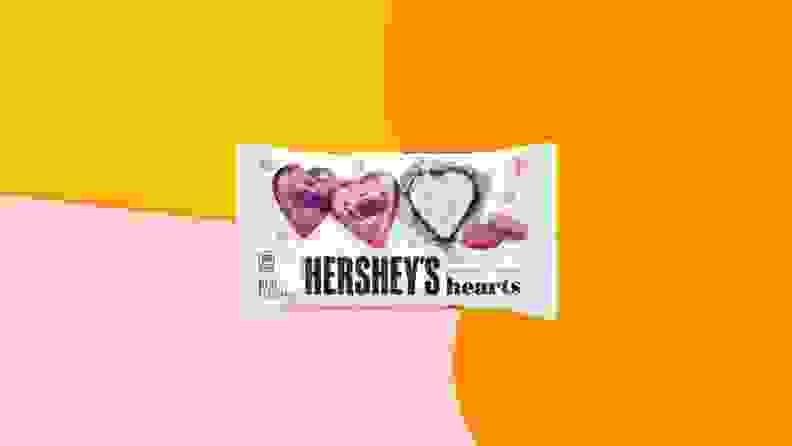 Hershey's Pink Cookies 'N' Creme Hearts packaging on an orange, yellow, and pink background