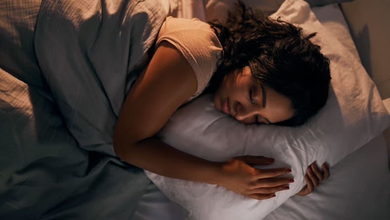 a woman curled up on her pillow in bed