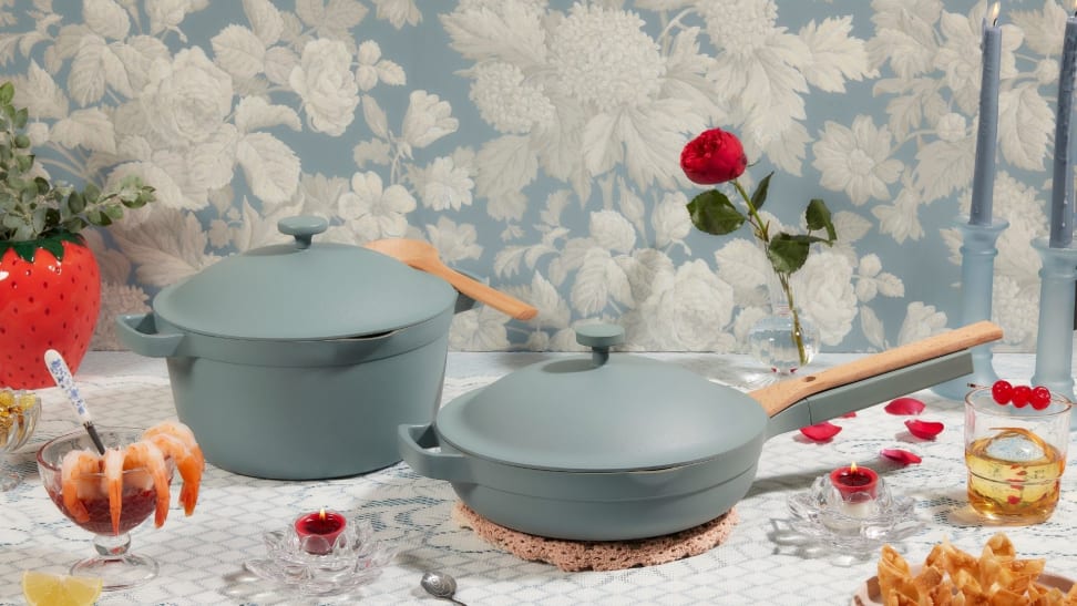 A light blue pan and a light blue pot with lids sit in the middle of a dreamy tablescape complete with shrimp cocktail, roses, and other appetizers.