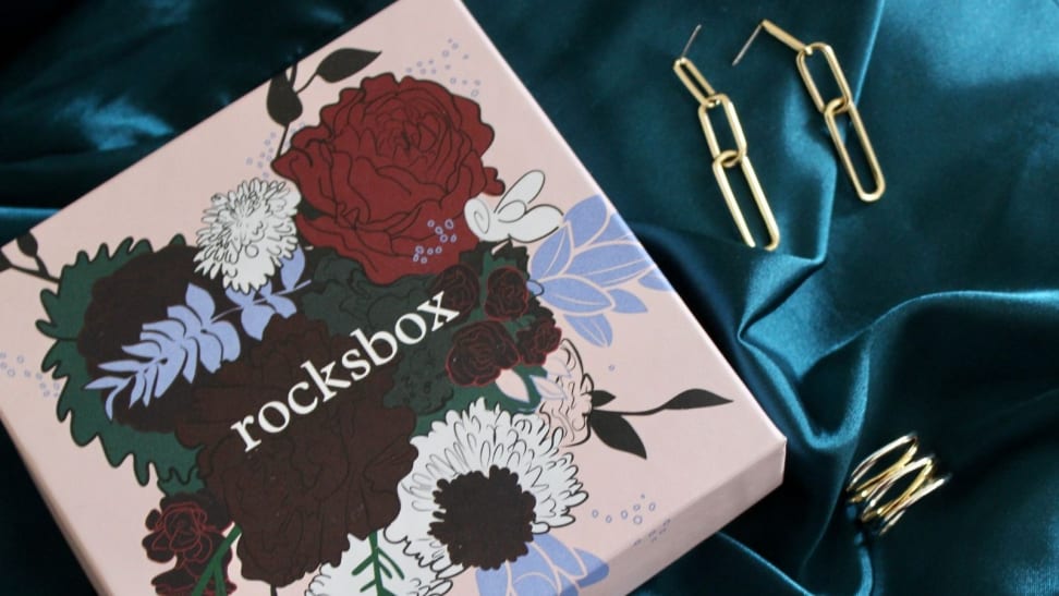 A pink box from Rocksbox with gold jewelry next to it