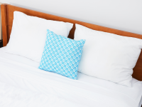 A bed with white sheets and a blue pillow