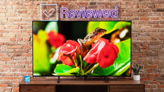 Hisense U7K Mini-LED TV sitting on top of wooden television stand in front of brick wall and Reviewed LED sign.