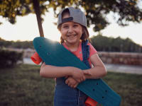 A girl smiles as she hugs her Penny Board beginner skateboard for kids.
