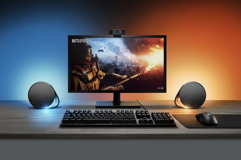 A pair of logitech g560, one of the best computer speakers, next to a monitor