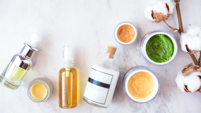 Lidless product jars sitting on the counter next to bottles containing oils and other liquids