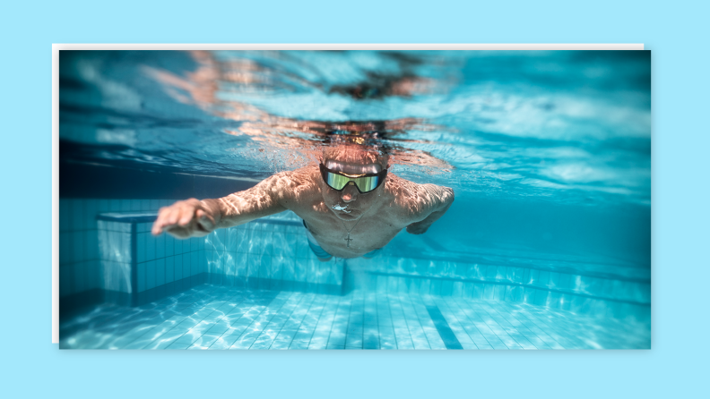 Person swimming underneath water's surface with goggles on.