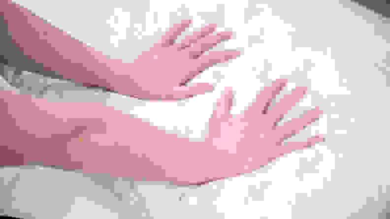 A pair of hands pressing down on a pillow.