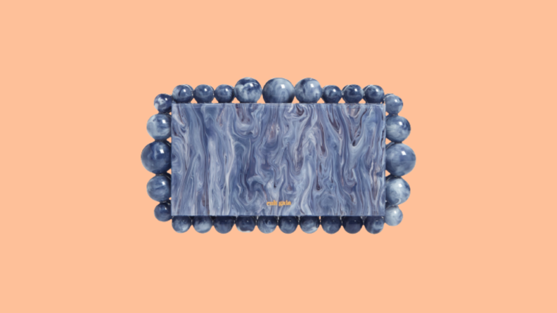 A slate-gray acrylic clutch purse with round beads along the outer perimeter.