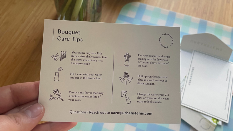 A person holding an UrbanStems bouquet care instructions card.
