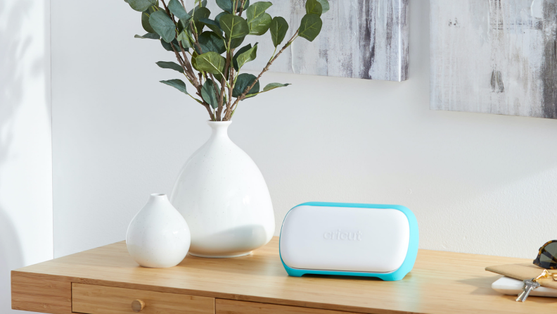 Cricut craft machine sitting on top of table next to white plant vases