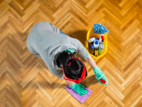 A woman cleans a hardwood floor on her knees