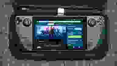 A black handheld gaming console with the screen turned on sitting inside of a carrying case.