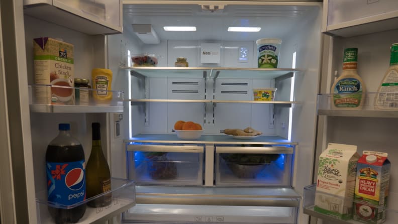 A shot of the interior of the fridge. Both doors are open wide and all the bins and shelves are fully stocked with food.
