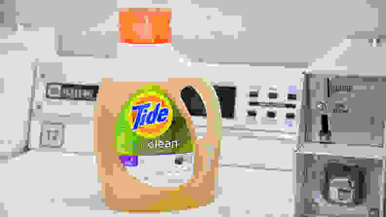 A bottle of Tide Purclean laundry detergent on a white top-loader washing machine.