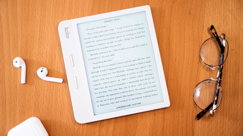 Tablet sitting on table next to earphones and glasses.