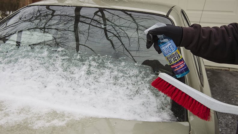 A shot of someone using a lock de-icer to de-ice a windshield.