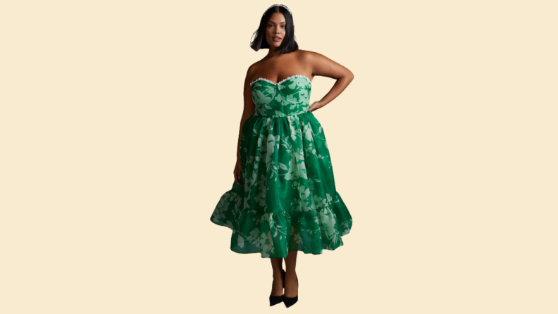 A woman wears a green midi dress with a floral print.