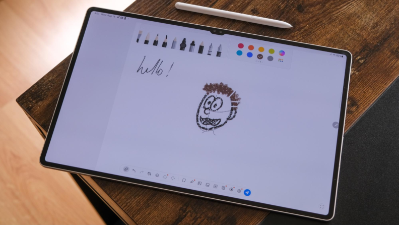 On screen is a doodle of person smiling within the art workspace of the Galaxy Tab S9 Ultra, which is next to white S Pen stylus.