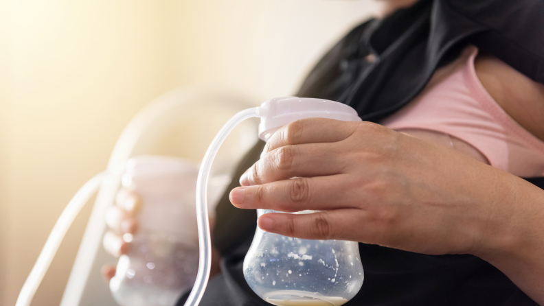 Person pumping milk from breasts into baby bottles using machines.