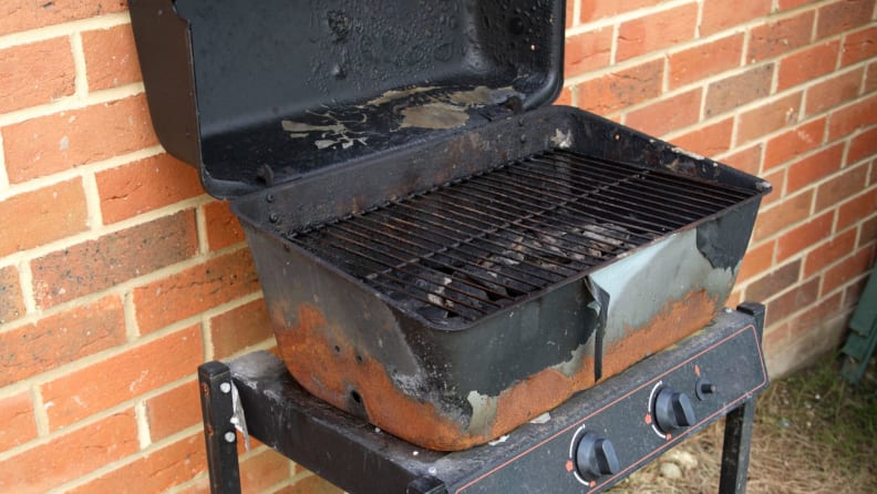 Cheap, rusty grill resting on a brick wall