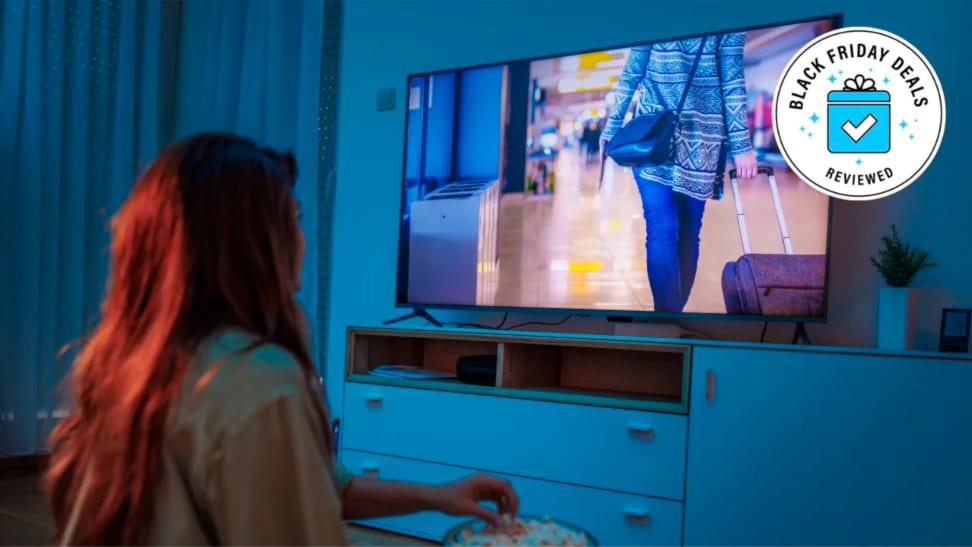 Woman with a bowl of popcorn watching a TV.