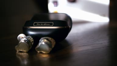 A pair of black and gold earbuds sit on a table