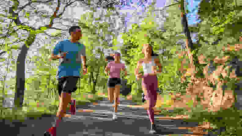 Three people running together on a trail.