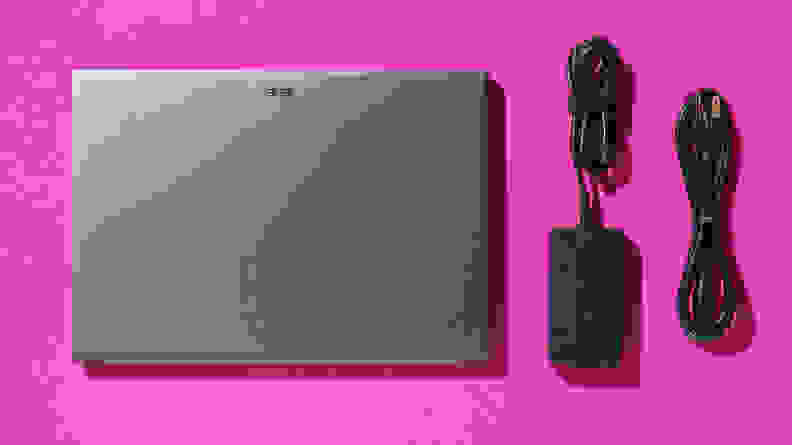 The Acer Swift X 14 laptop next to power cords on a pink background.