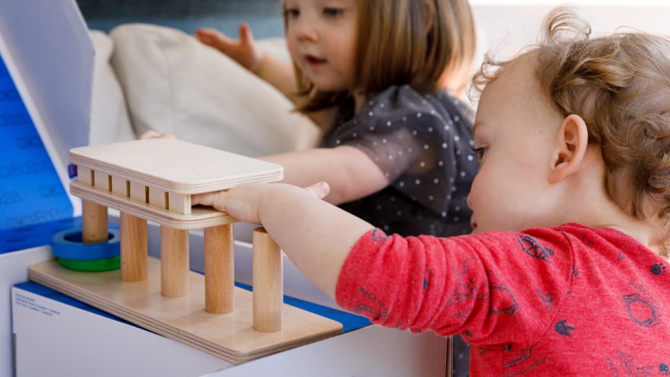 Two children play with a Monti Kids toy box activity.