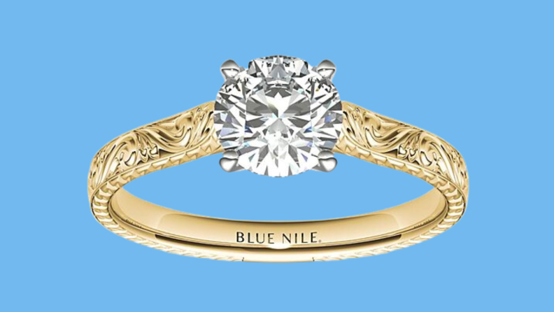 An image of a delicately carved golden band showcasing a small diamond.