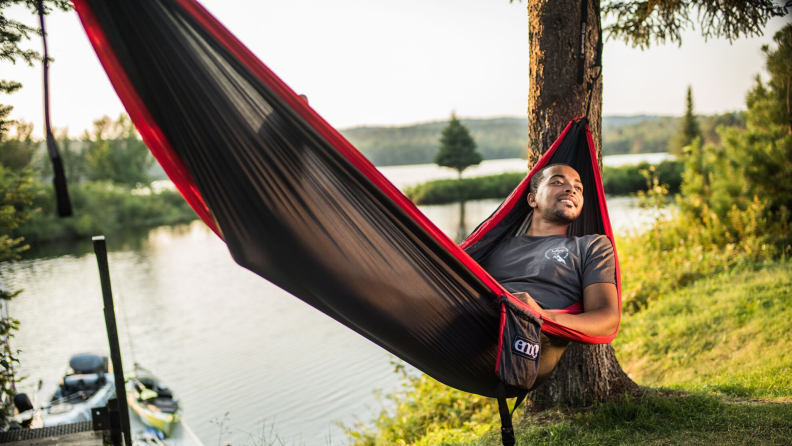 Man sitting in ENO hammock connected by trees.