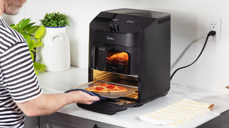 Person pulling out a slice of pizza from the Midea air fryer