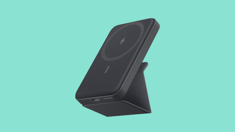 A black Anker magnetic wireless portable phone charger fixed to a mount on a dark teal background.