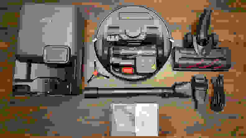 A black robot vacuum plus attachments on a wood floor