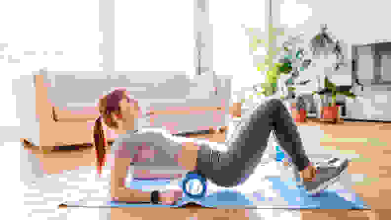 A woman foam rolling her back.