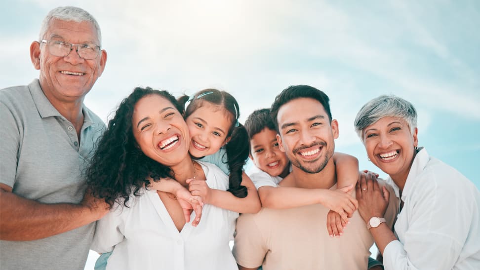 A family portrait of six people, including two seniors, two adults, and two children, all wearing pale earth tones.