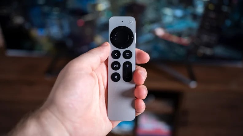 A hand holding a small TV remote