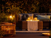 Trendy outdoor patio furniture, lights, lanterns and candles in the garden at night.