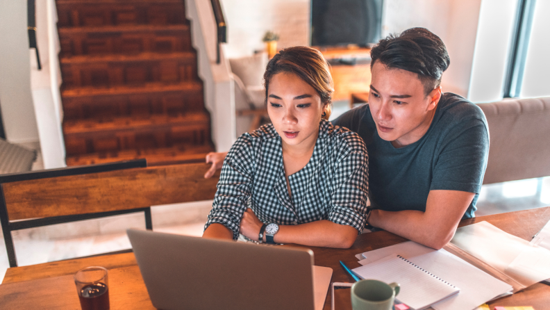 Couple looking at computer together at table.