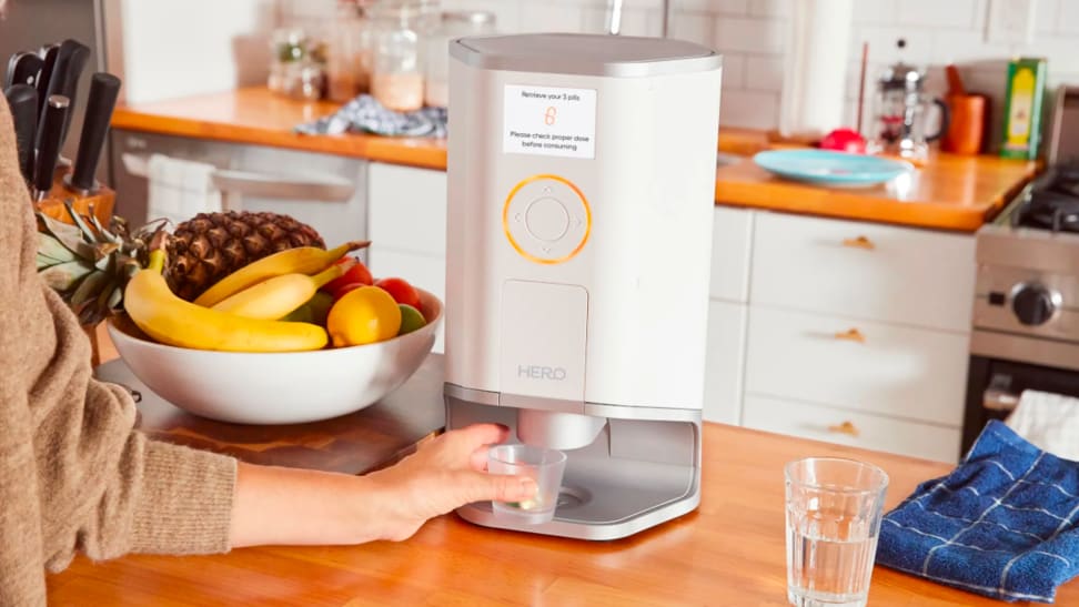 A person collects medication from a pill dispenser.