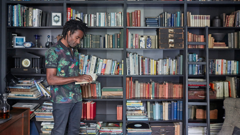 A person pulls a book from a bookshelf.