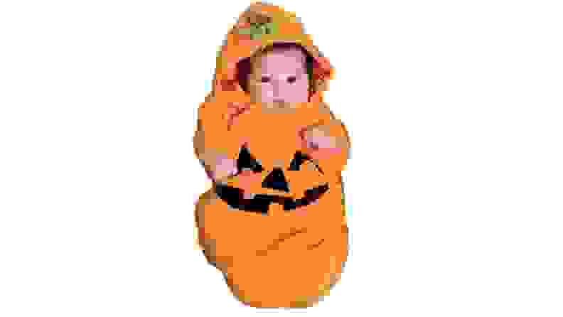 A baby in a pumpkin pullover costume.